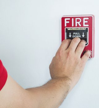 Personne activant le boîtier d'alarme incendie