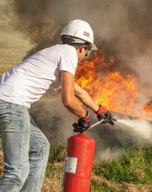 Personne en formation incendie en train d'éteindre un feu avec un extincteur