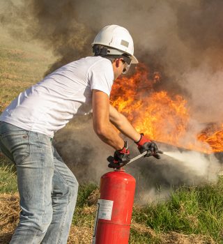 Personne en formation incendie en train d'éteindre un feu avec un extincteur